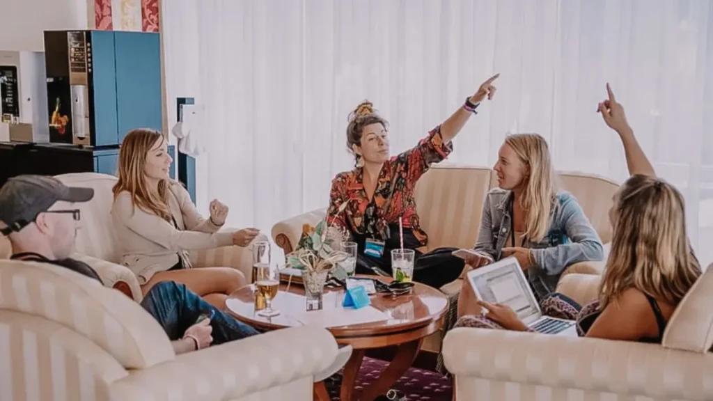 Gesprächsrunde von Menschen mit Laptops bei einer Workation - strukturierter Austausch über Arbeiten im Ausland