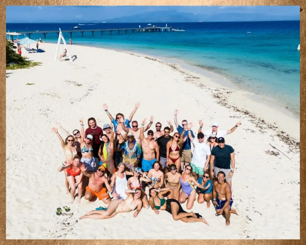 Gruppe von Menschen an einem Strand während einer Workation-Reise, Community-Erlebnis zwischen Arbeit und Reisen