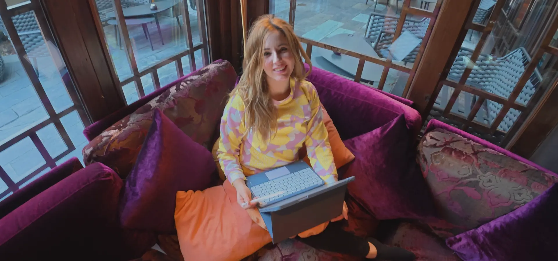 Frau arbeitet mit Laptop auf Sofa und kombiniert Beauty Beratung mit Content Marketing für Präsenz vor der Kamera