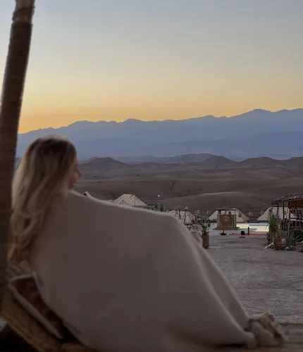 Frau blickt von hinten in eine weite Landschaft mit Bergen
