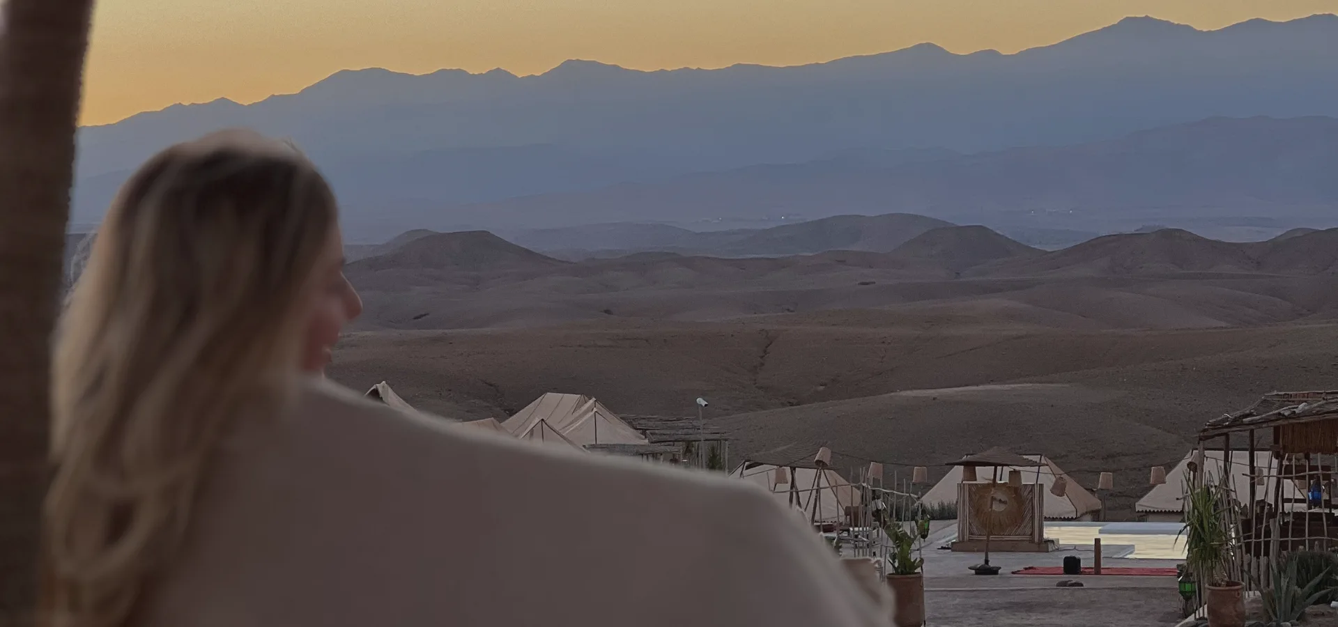 Frau blickt von hinten in eine weite Landschaft mit Bergen