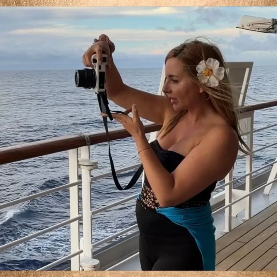 Frau filmt sich mit Kamera auf einem Schiff mit Blick aufs Meer